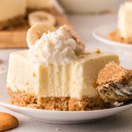 No Bake Banana Pudding Cheesecake Bar on a white plate with a bite missing