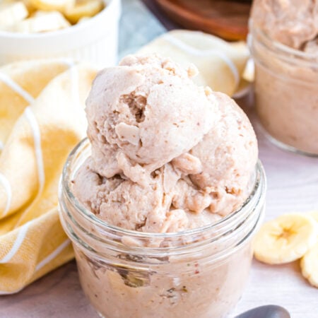 Banana Ice Cream in a glass bowl on table with slices of bananas around table