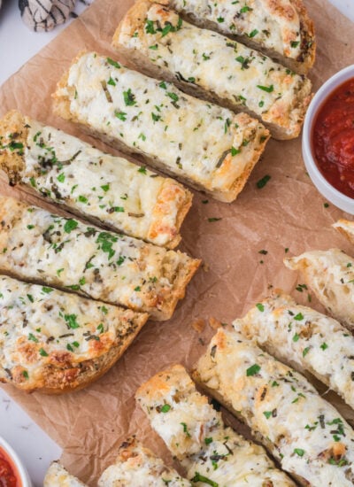 Cheesy Garlic Bread sliced on a table with marinara sauce