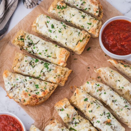 Cheesy Garlic Bread sliced on a table with marinara sauce