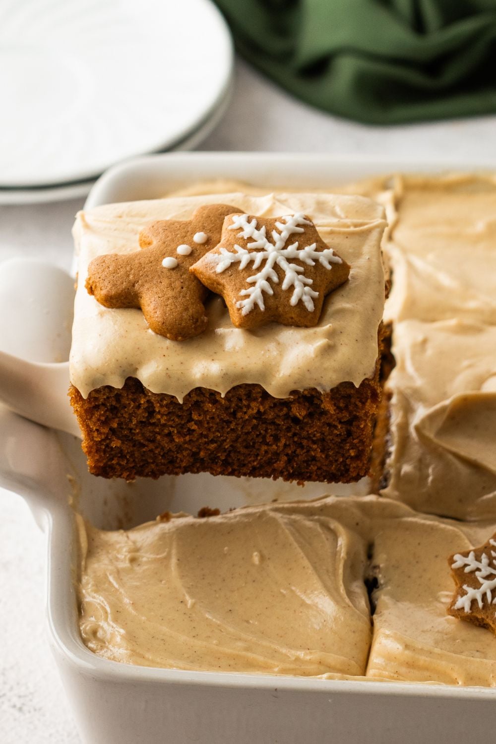 Gingerbread Cake with Cream Cheese Frosting being lifted out of pan to serve up a slice of cake 