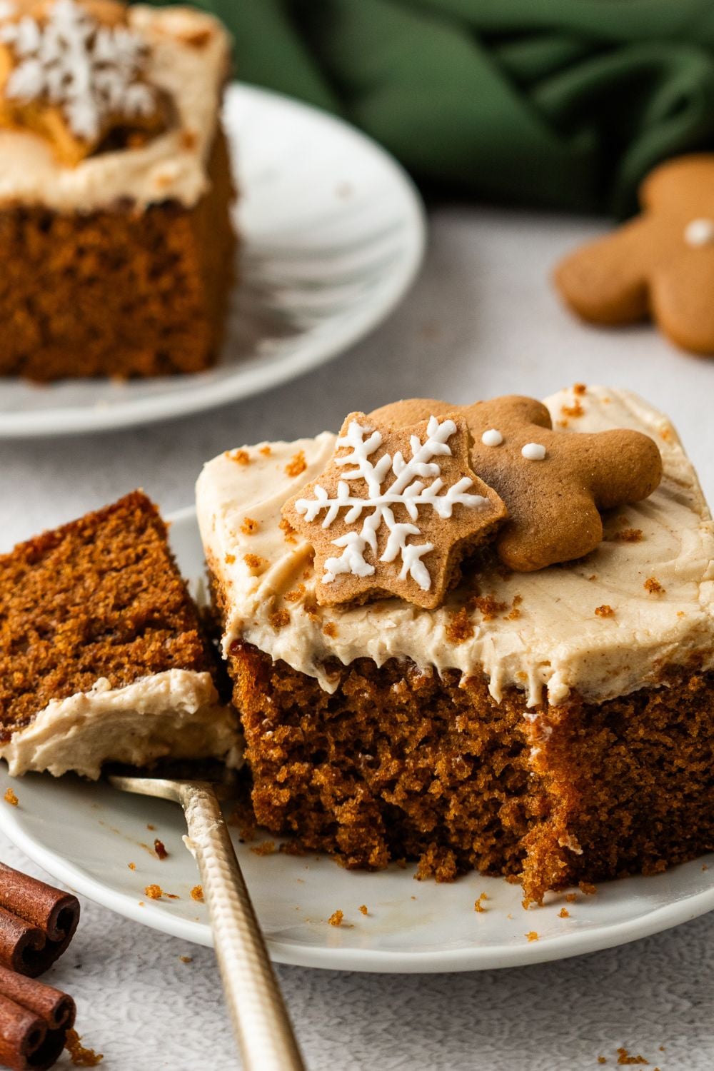 slice of Gingerbread Cake with Cream Cheese Frosting with a bite taken off sitting on fork on table 