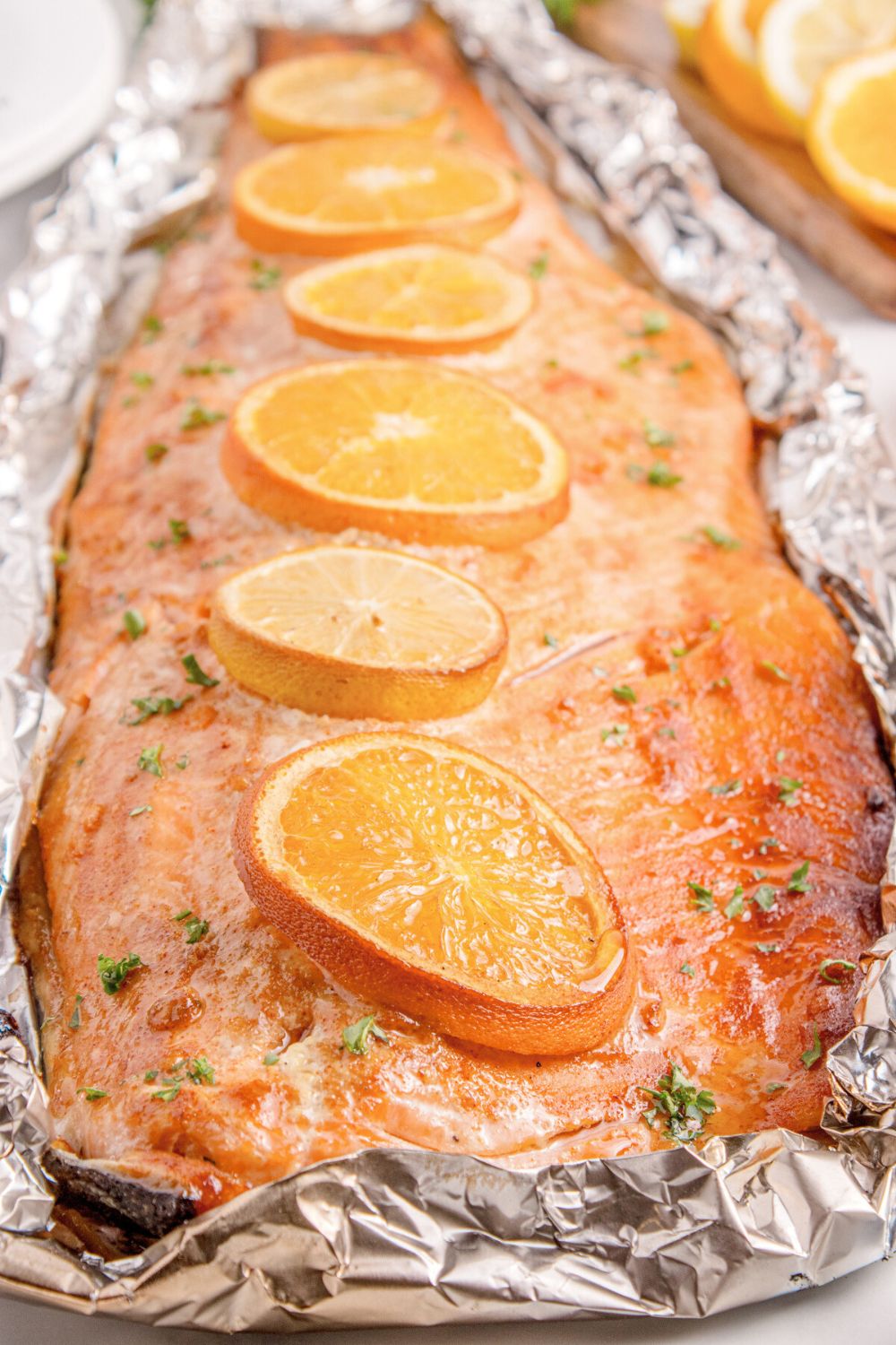 Grilled Honey Mustard Salmon in Foil sitting on table with oranges to side of table 