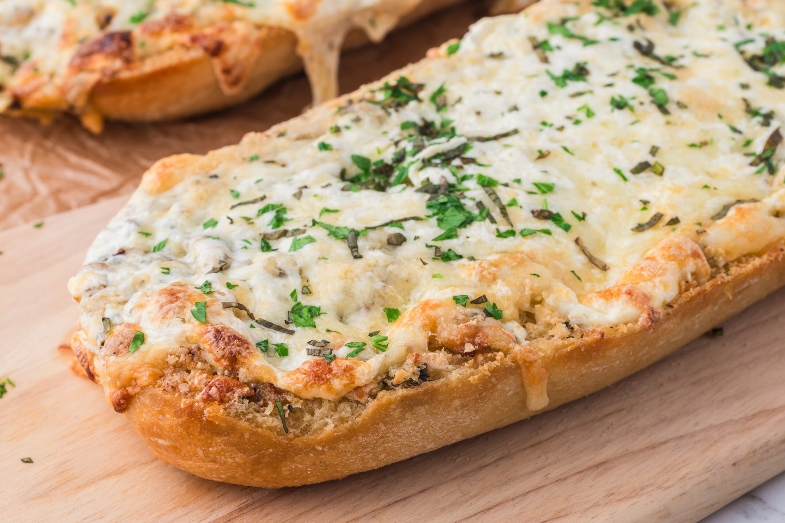 a cutting board with  a loaf of the  Cheesy Garlic Bread on it