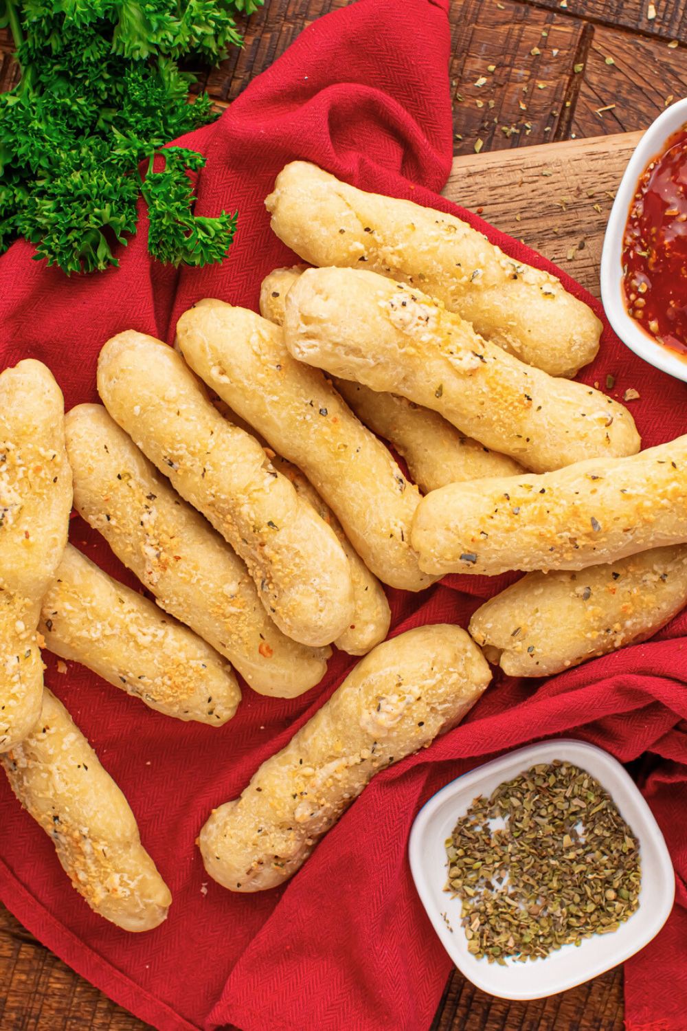 2 Ingredient Garlic Parmesan Breadsticks on table with a red towel under and parsley to side 