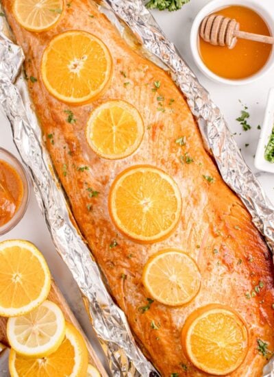 Grilled Honey Mustard Salmon in Foil on table with honey, citrus wedges, etc.