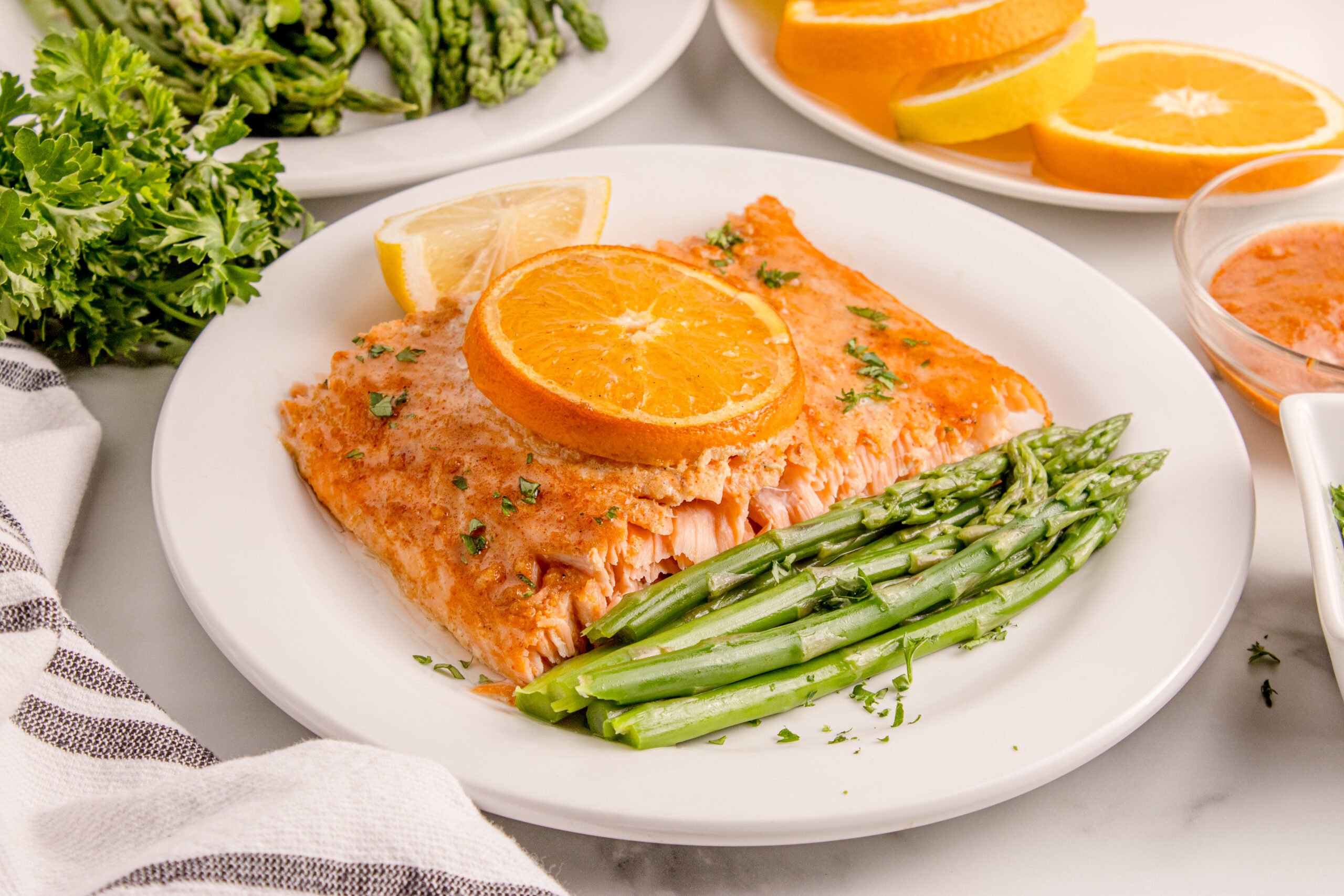 Grilled Honey Mustard Salmon on a white plate with asparagus and citrus wedges