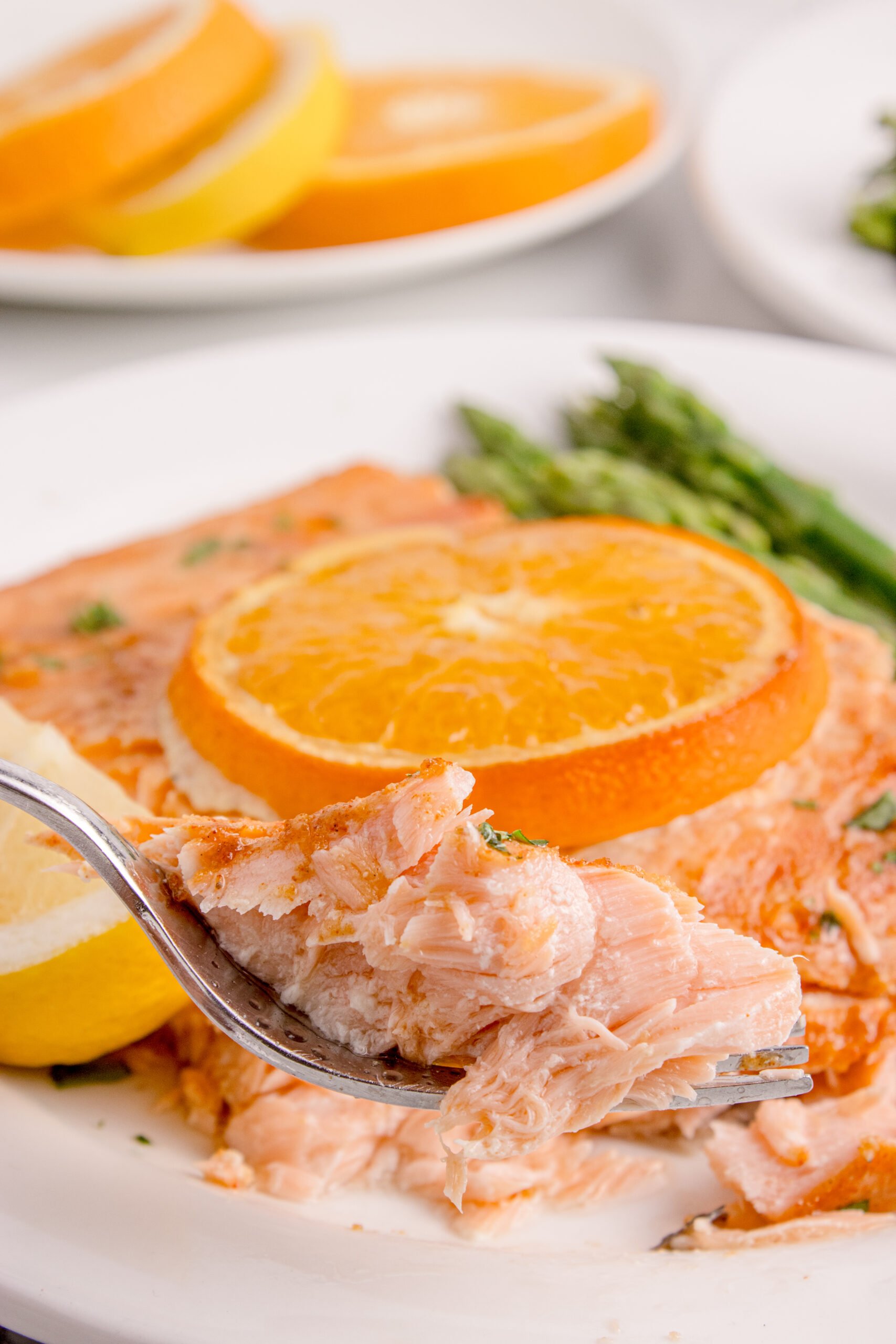 Grilled Honey Mustard Salmon on a white plate with a bite being lifted by a fork