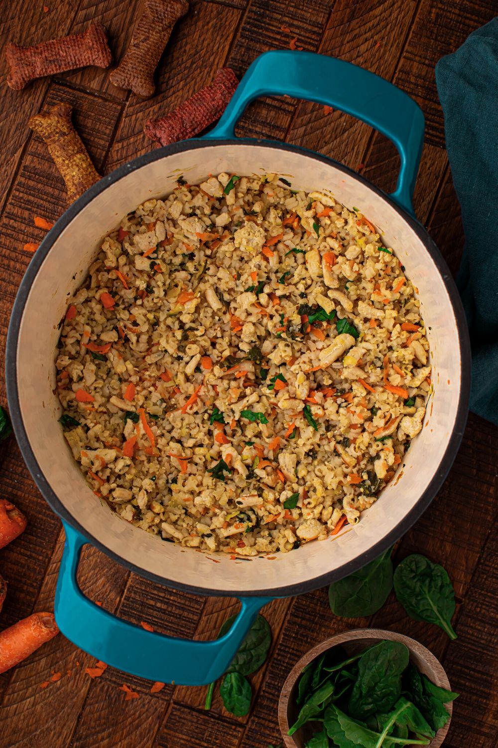 looking down at table with Homemade Turkey and Rice Dog Food with Veggies in a pot, dog treats, and more around the table 