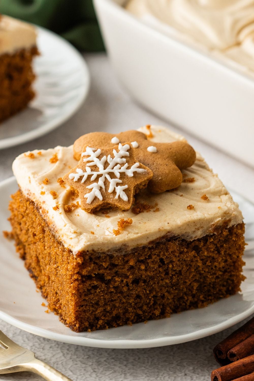 slices of Gingerbread Cake with Cream Cheese Frosting  on plates sitting on table with main cake in pan 