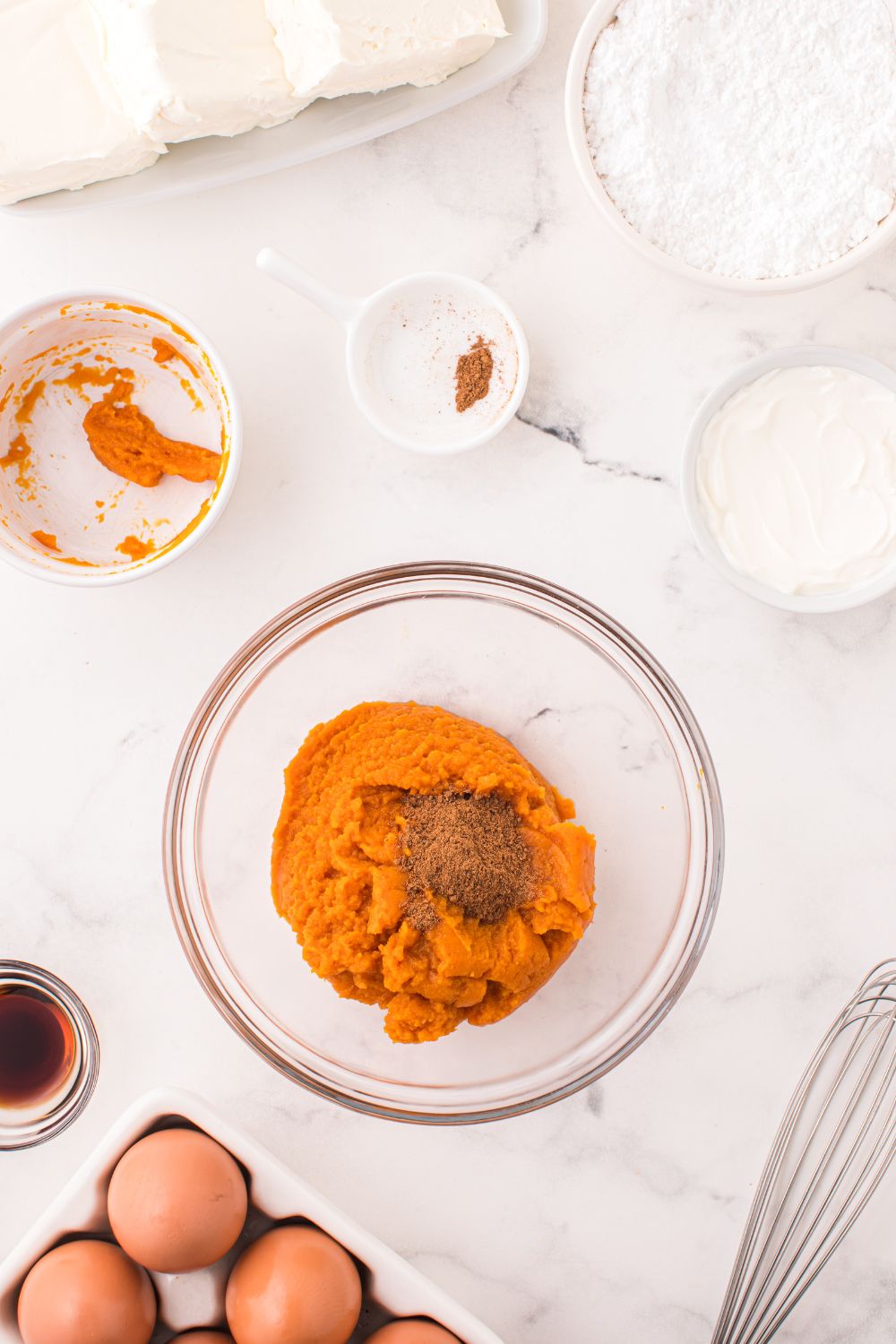 pumpkin puree and spices in a glass bowl on table for making Swirled Pumpkin Cheesecake Bars