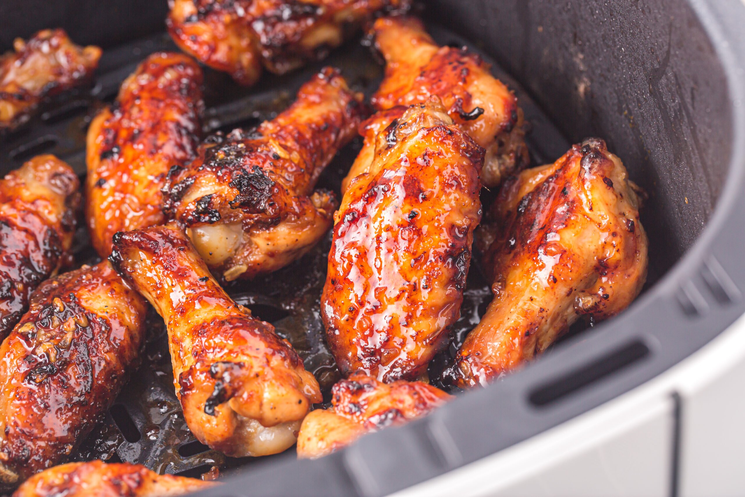 an Air Fryer Basket with the cooked Air Fryer Honey Garlic Chicken Wings inside