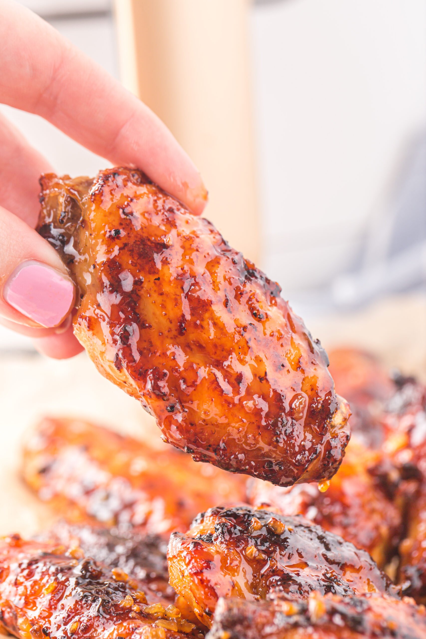 Hand holding up one Air Fryer Honey Garlic Chicken Wing