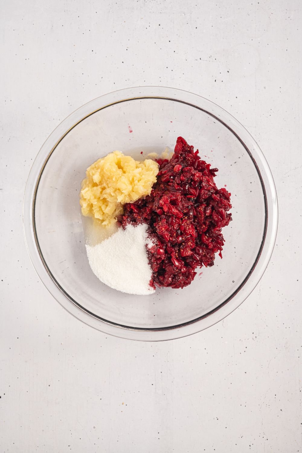 crushed cranberry mixture, sugar, and crushed pineapple in a glass bowl 