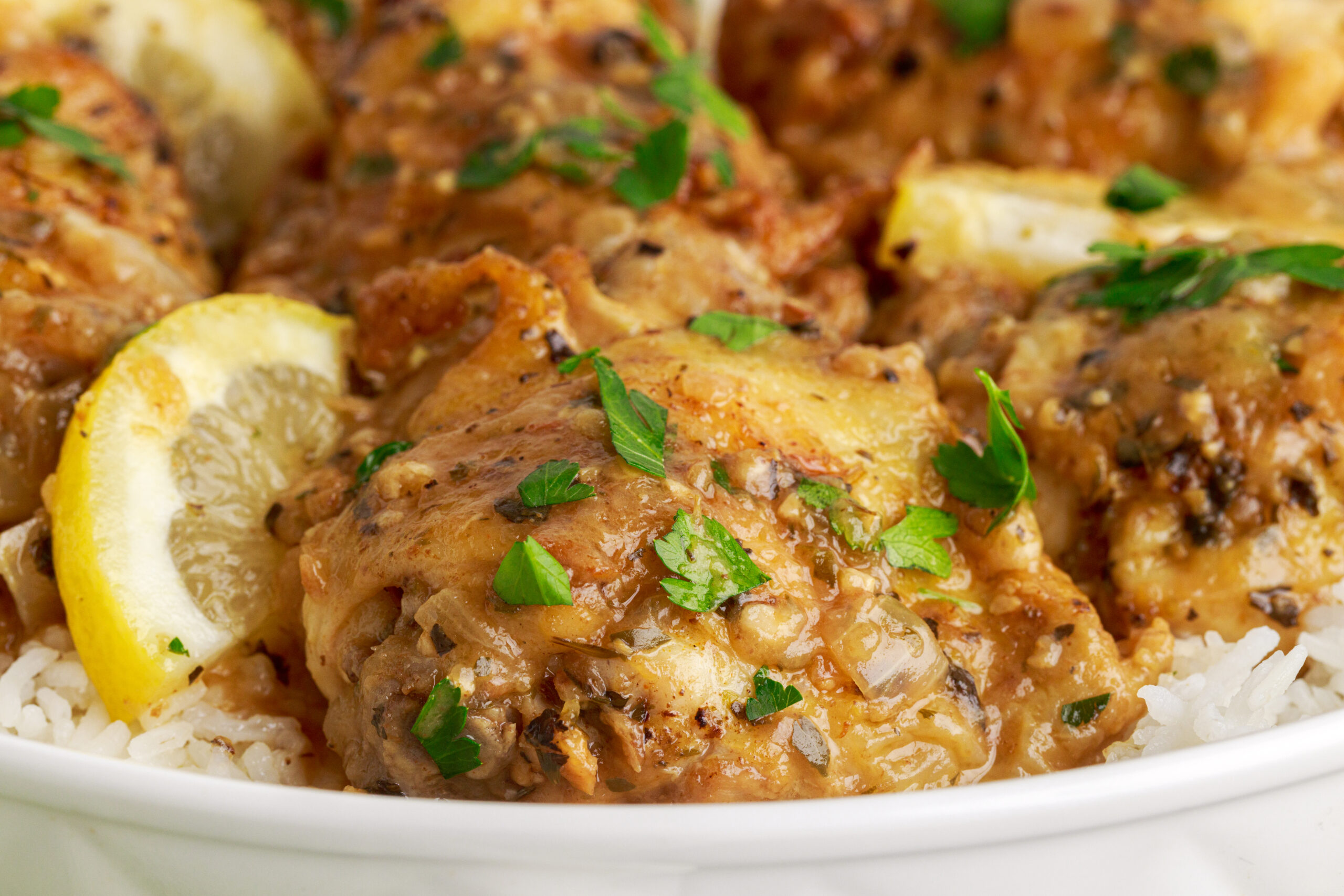 close up shot of the  Instant Pot Lemon Butter Chicken in a  white serving dish sitting on a table 
