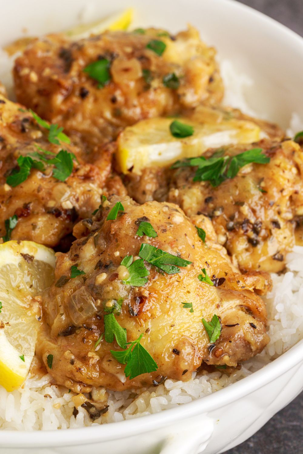 close up of Instant Pot Lemon Butter Chicken on plate with lemon wedges around the chicken 