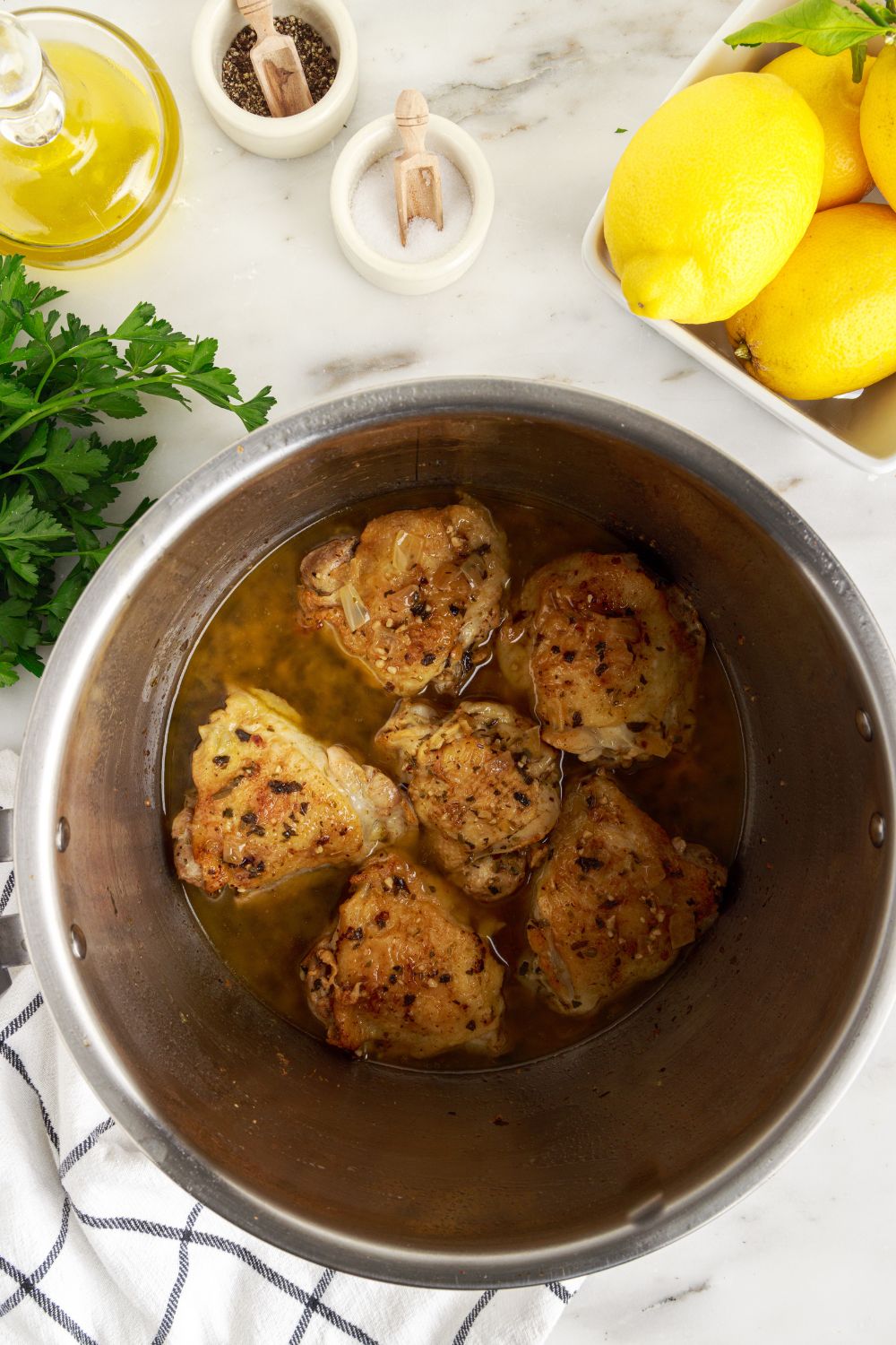 looking down into Instant Pot Lemon Butter Chicken that has been cooked with a bowl of lemons to side on table 