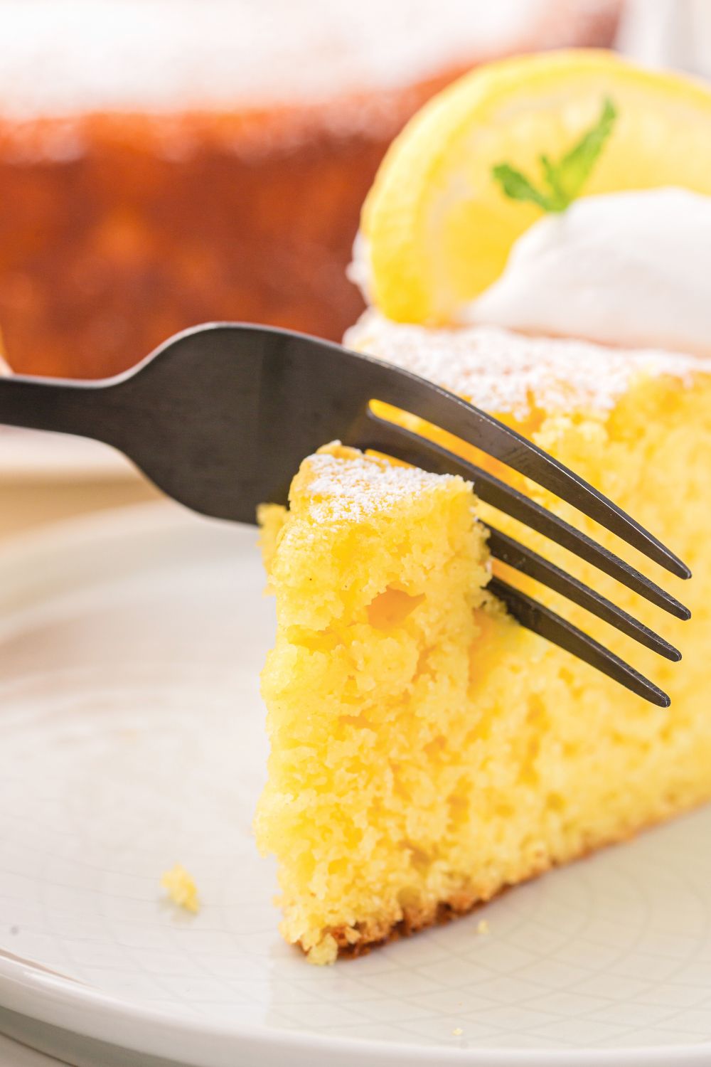 piece of Italian Lemon Ricotta Cake with a fork cutting into it 