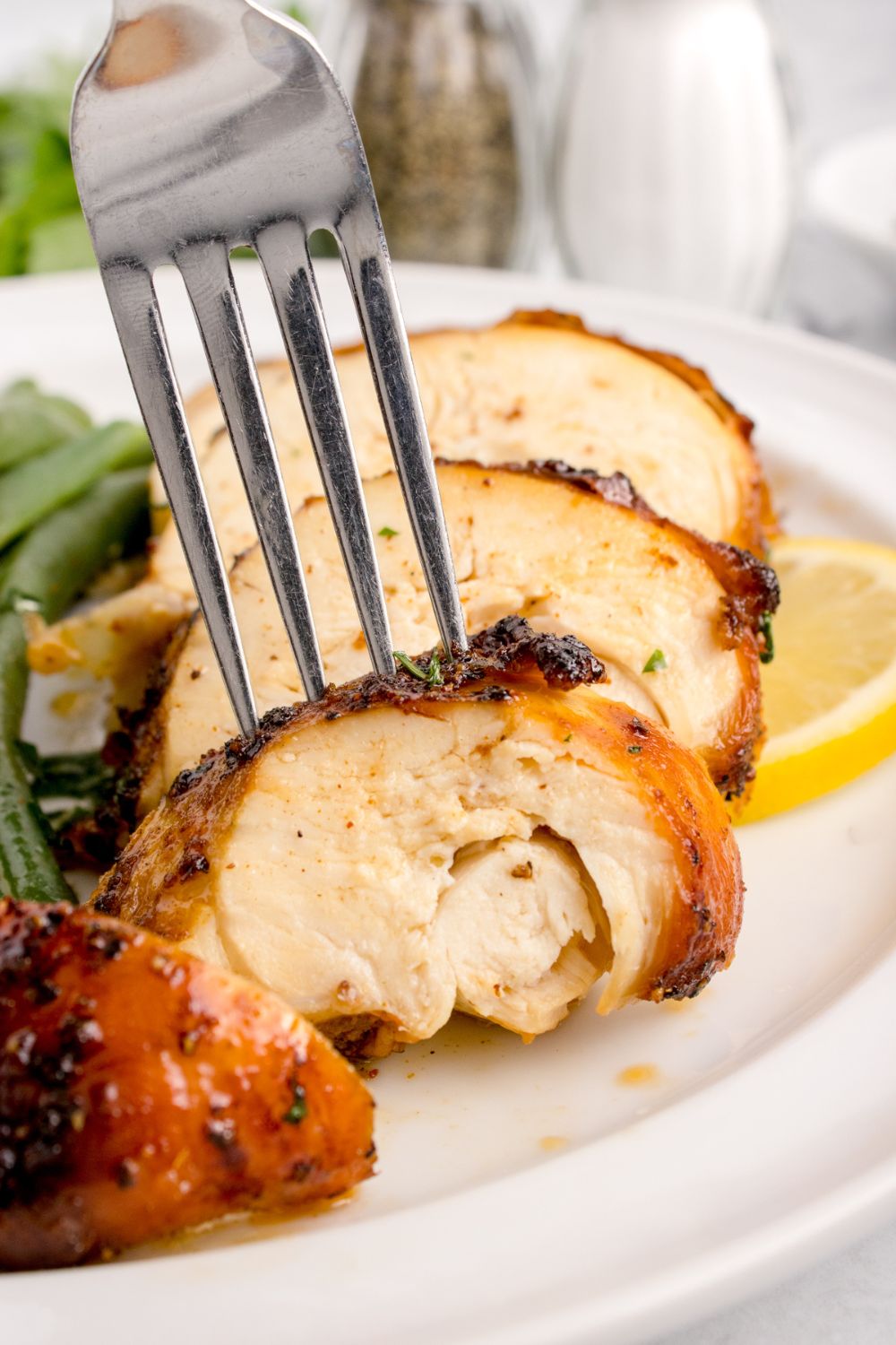sliced Air Fryer Chicken Breast into strips with a fork poking into one of the chicken slices 