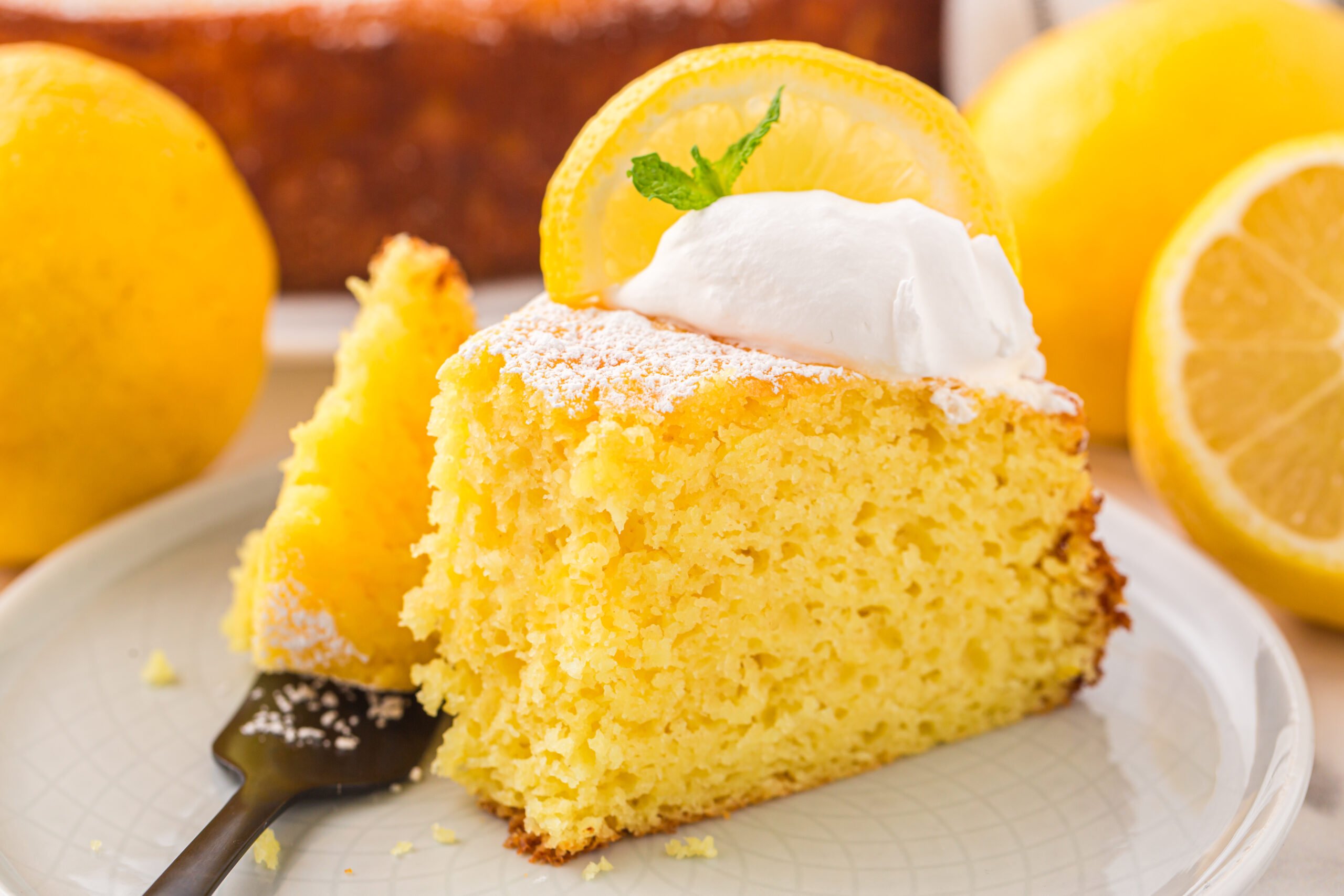 slice of Italian Lemon Ricotta Cake on a white plate with a fork taking a bite out of the slice 