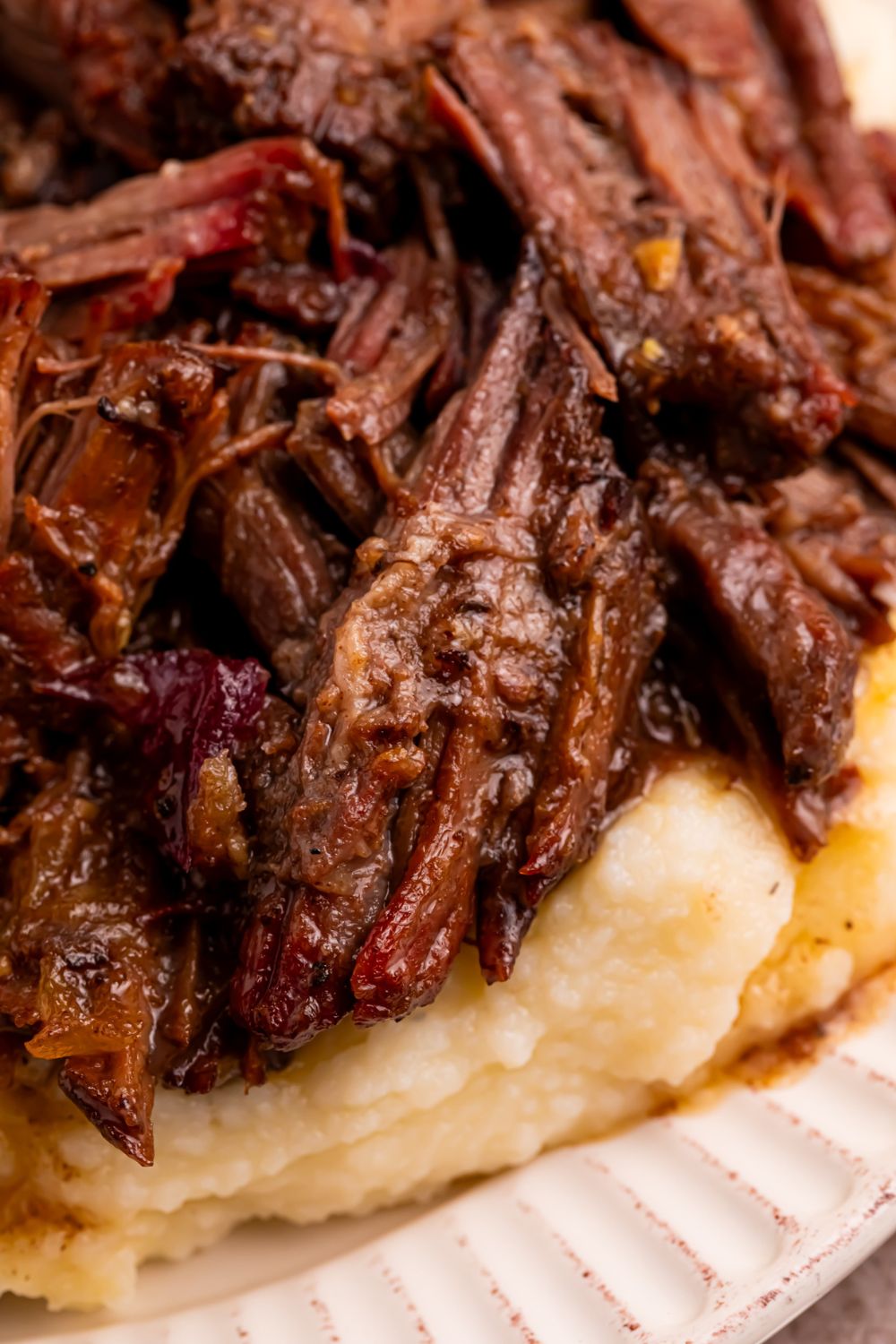 Cranberry Pot Roast shredded and on plate with mashed potatoes under it 