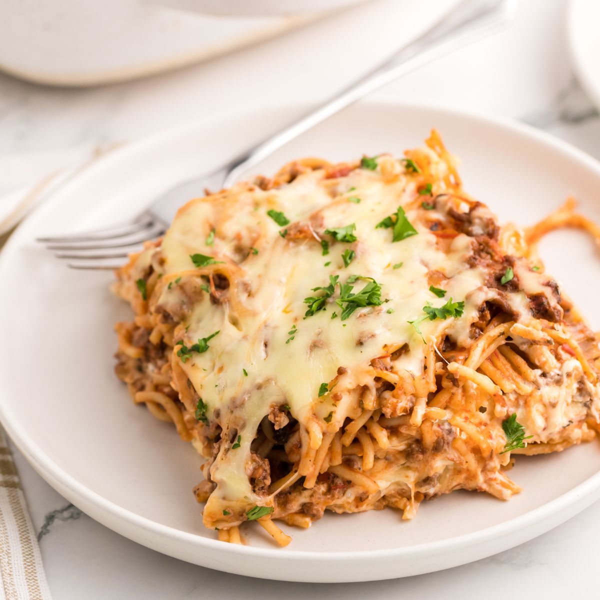 Million Dollar Spaghetti Casserole on a plate with fork on side 