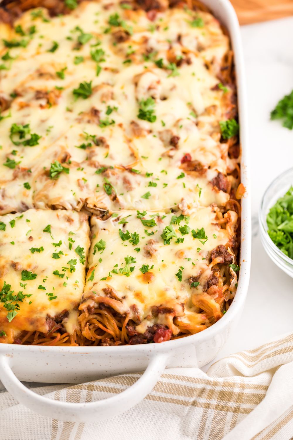 Million Dollar Spaghetti Casserole in pan with parsley sprinkled on top cut into squares 