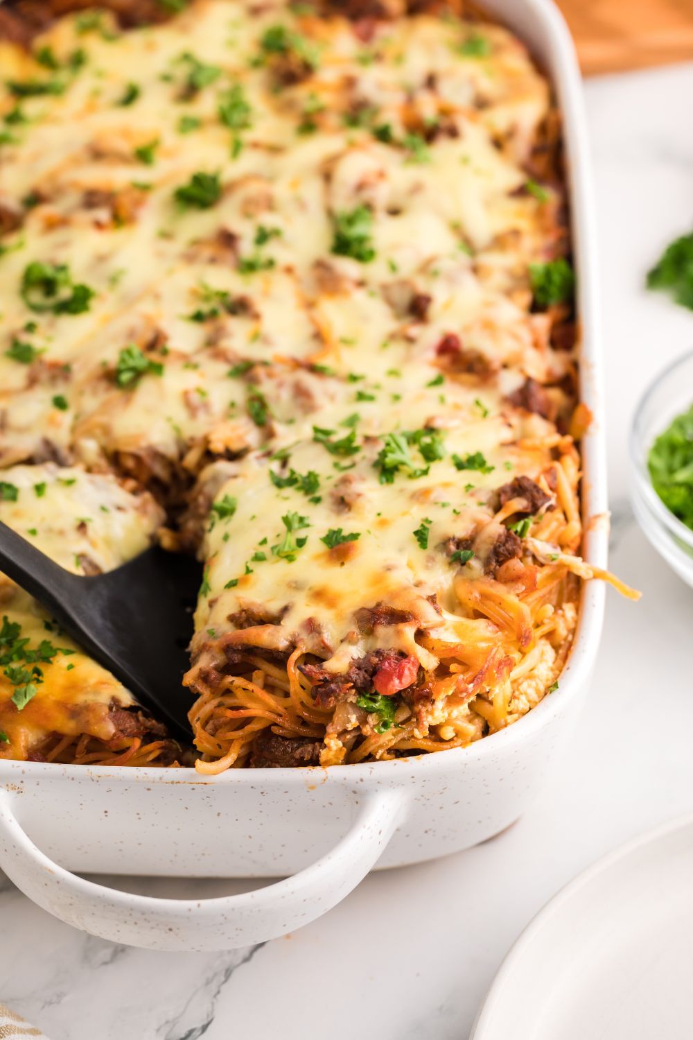 Million Dollar Spaghetti Casserole in a pan lifting some up with spatula 