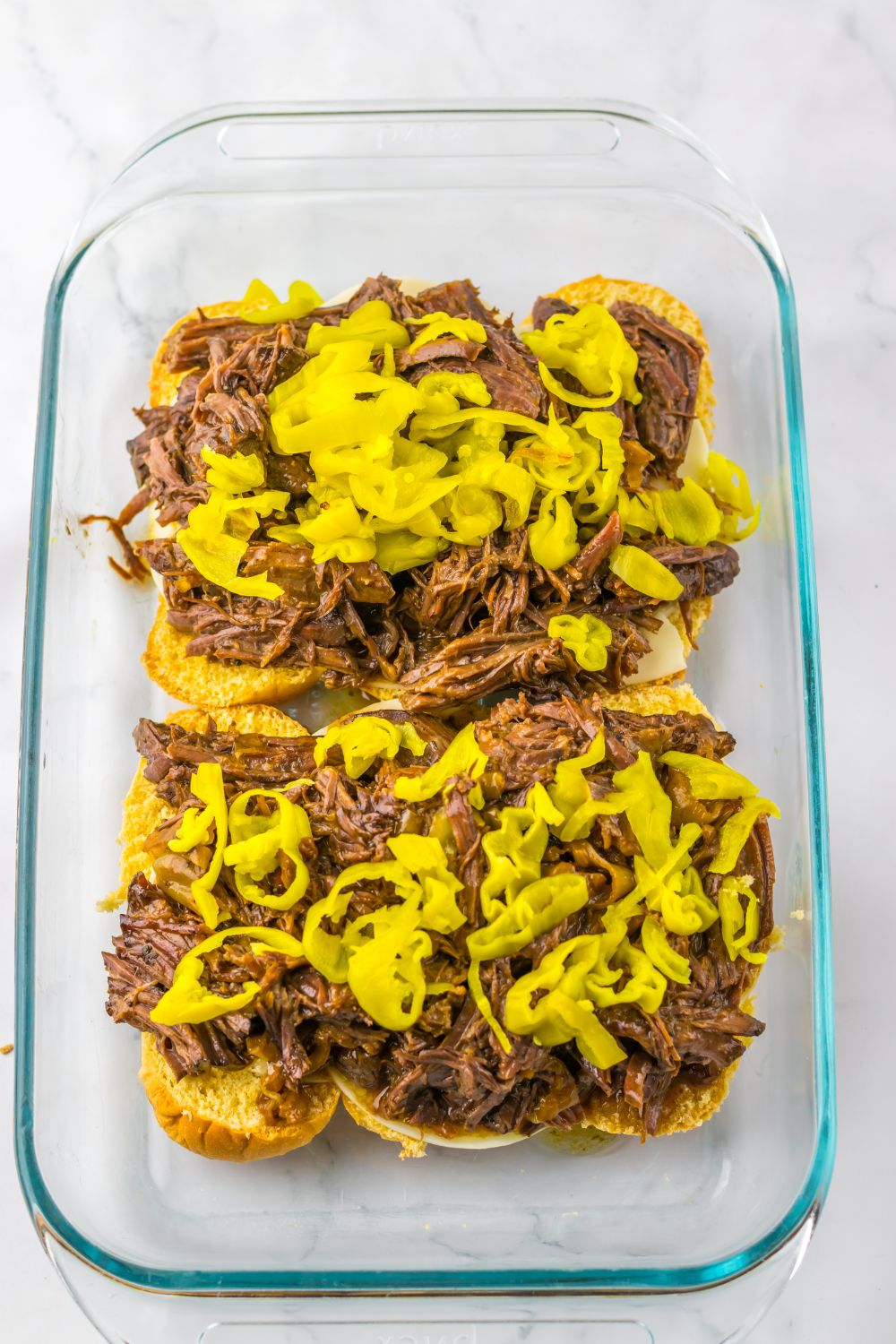 overhead look of pan with meat and peppers on top of slider buns 
