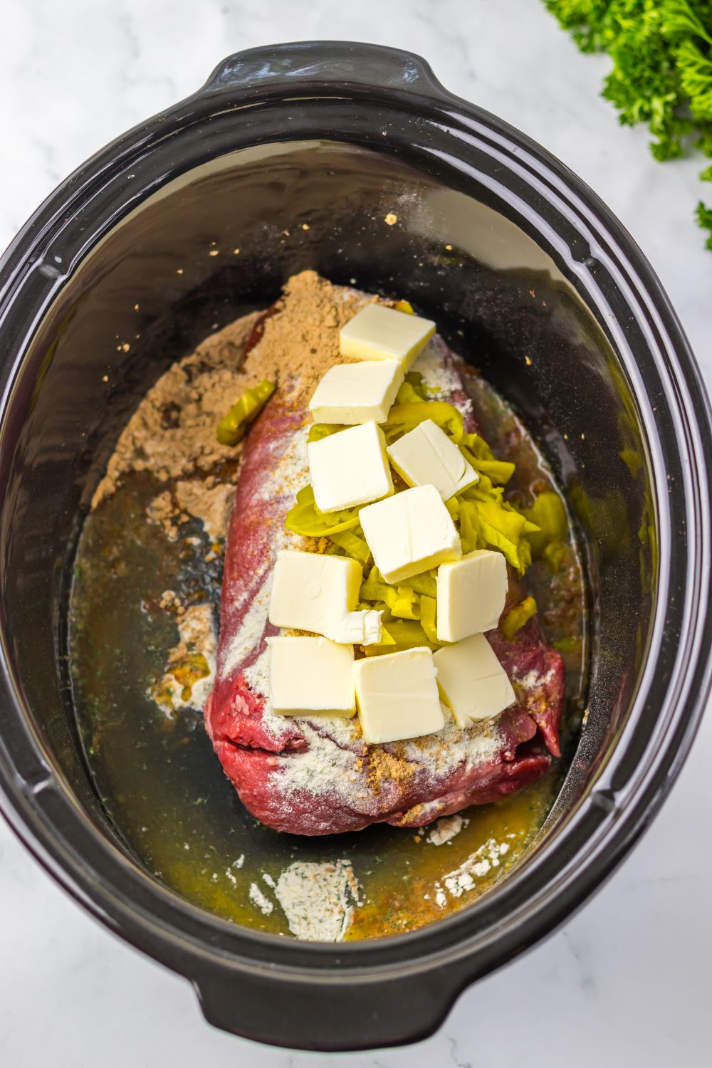 raw pot roast with sauce, butter and peppers
