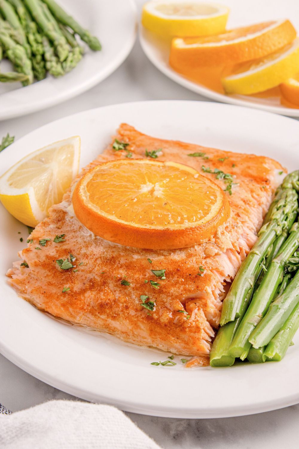 side view of table with a plate of Grilled Honey Mustard Salmon, a side of asparagus, and lemon wedge to side 