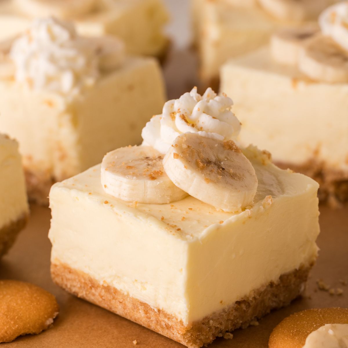 No Bake Banana Pudding Cheesecake Bars sliced and placed on table with vanilla wafers around table 