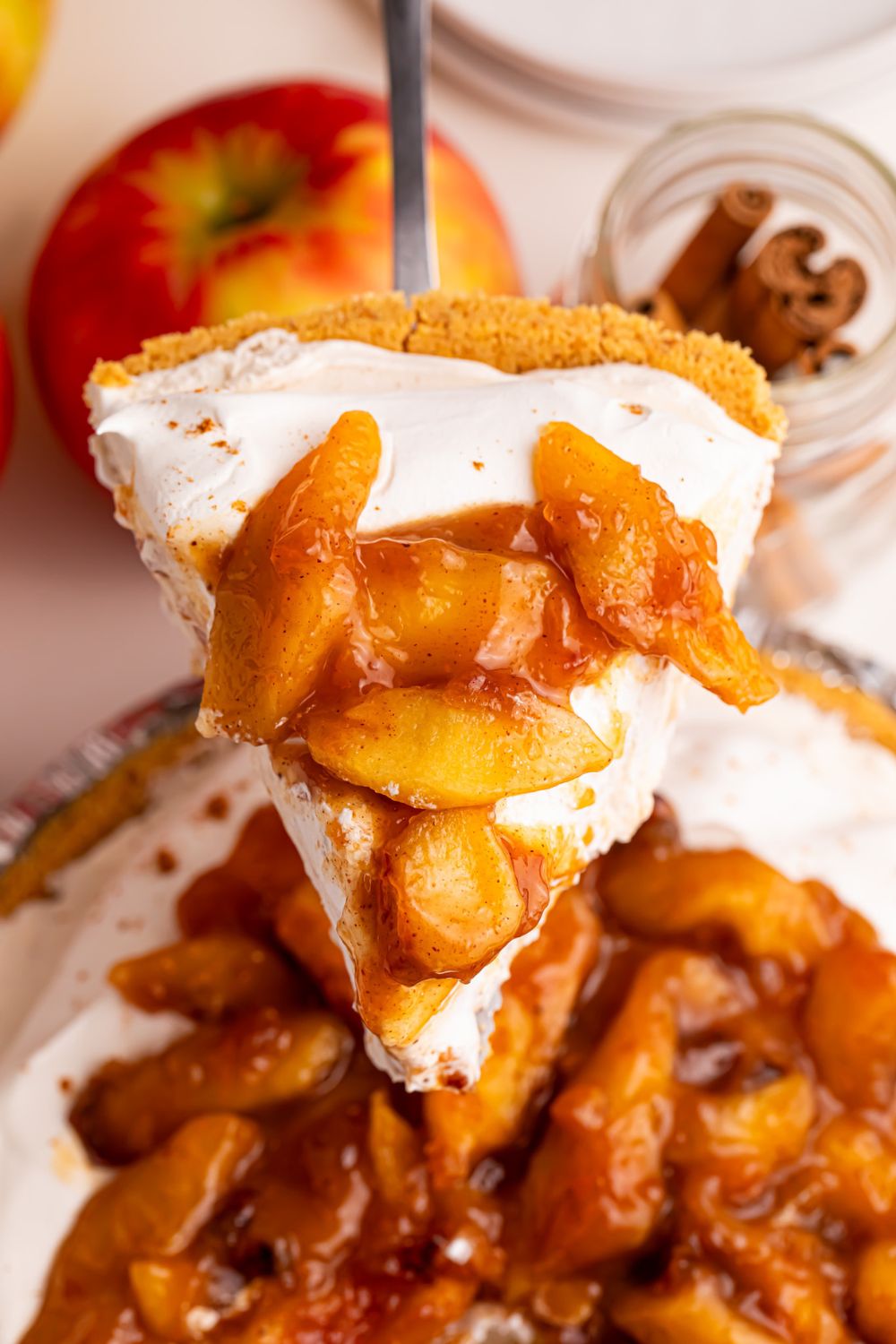 slice of No Bake Apple Cheesecake pie being lifted out of the pie plate on table 