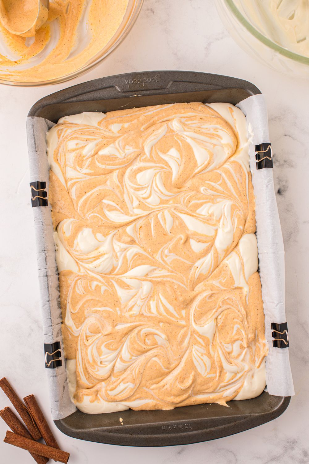 raw batter for Swirled Pumpkin Cheesecake Bars in pan on table
