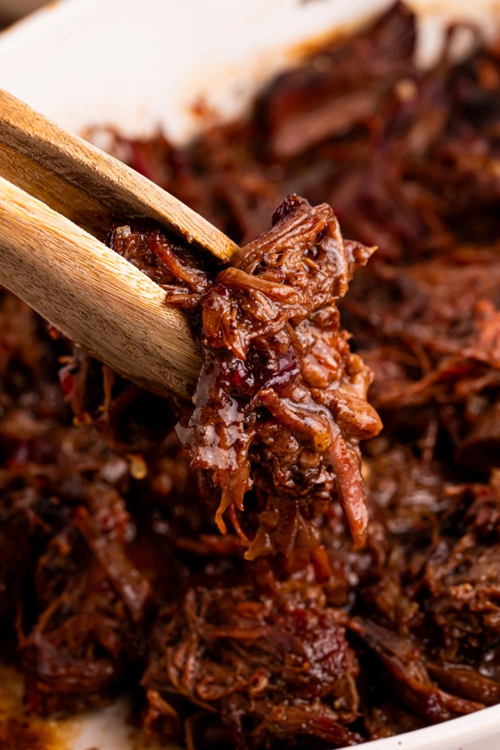 Cranberry Pot Roast shredded with tongs picking up some meat 