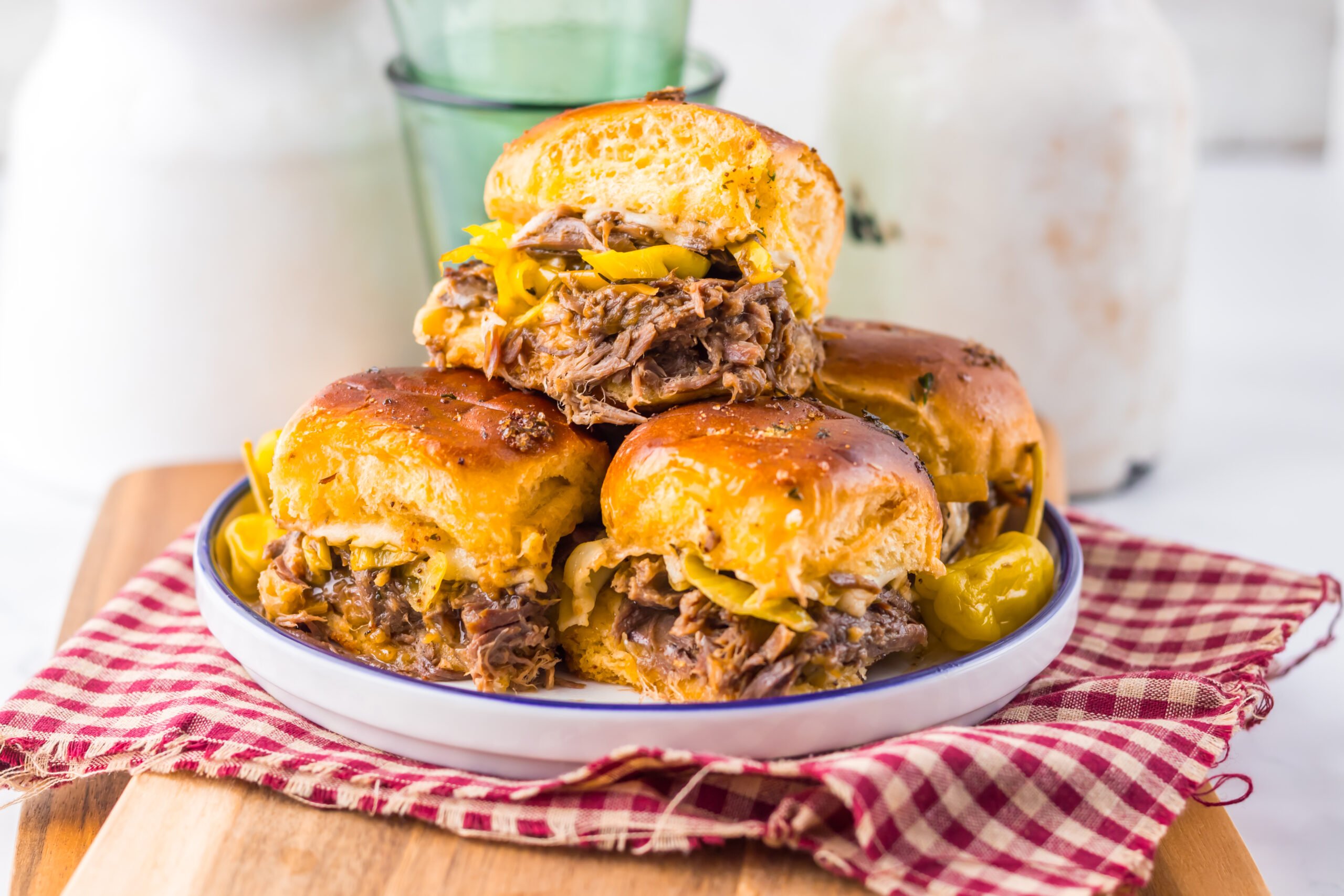 close up of Slow Cooker Mississippi Pot Roast Sliders on a plate with a red checkered towel under it 