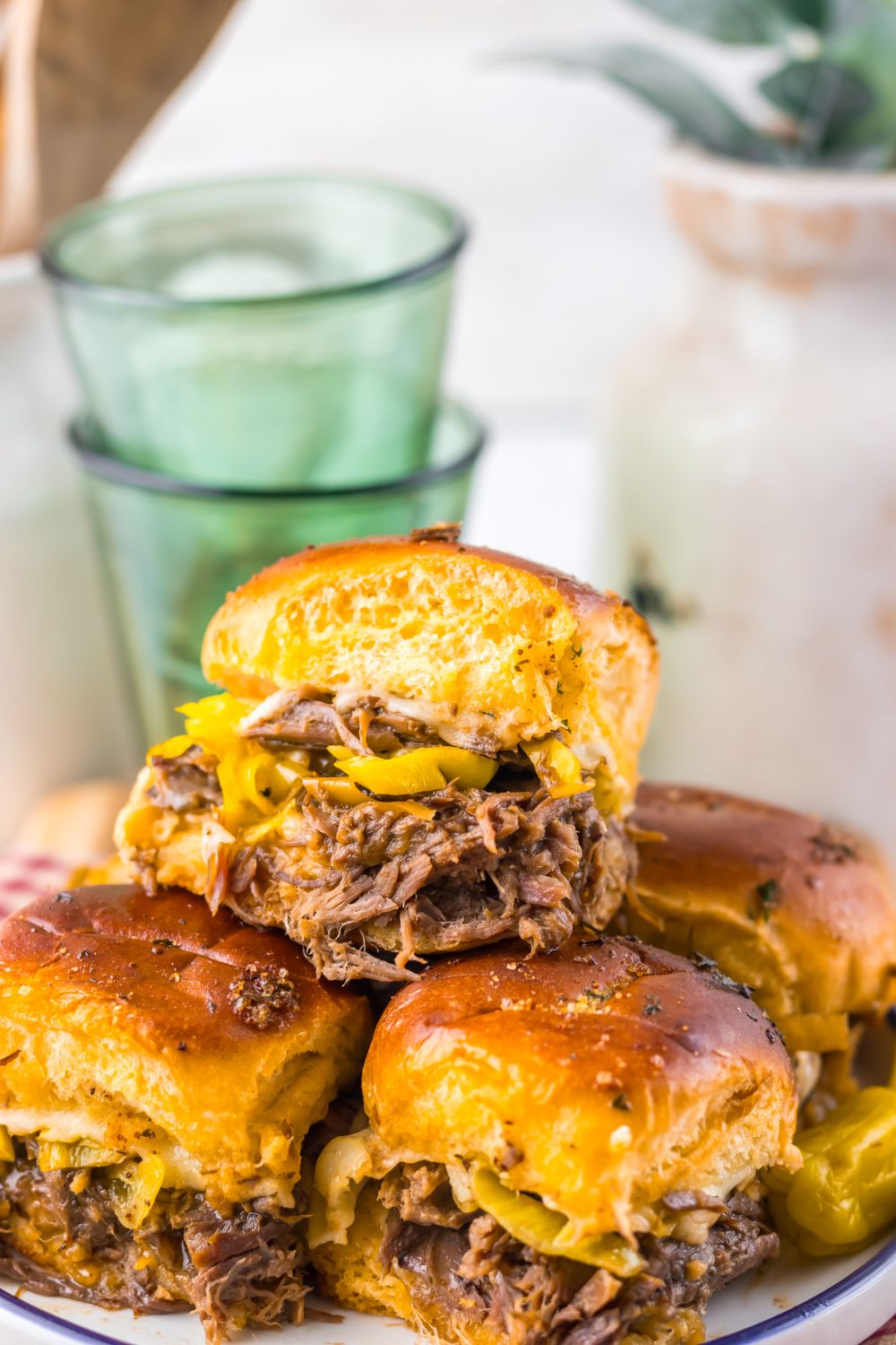 Slow Cooker Mississippi Pot Roast Sliders stacked on a plate with a close up of sliders on table 