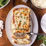 Stuffed Philly Cheesesteak Meatloaf on a white platter on wooden table that is partly sliced and ready to serve