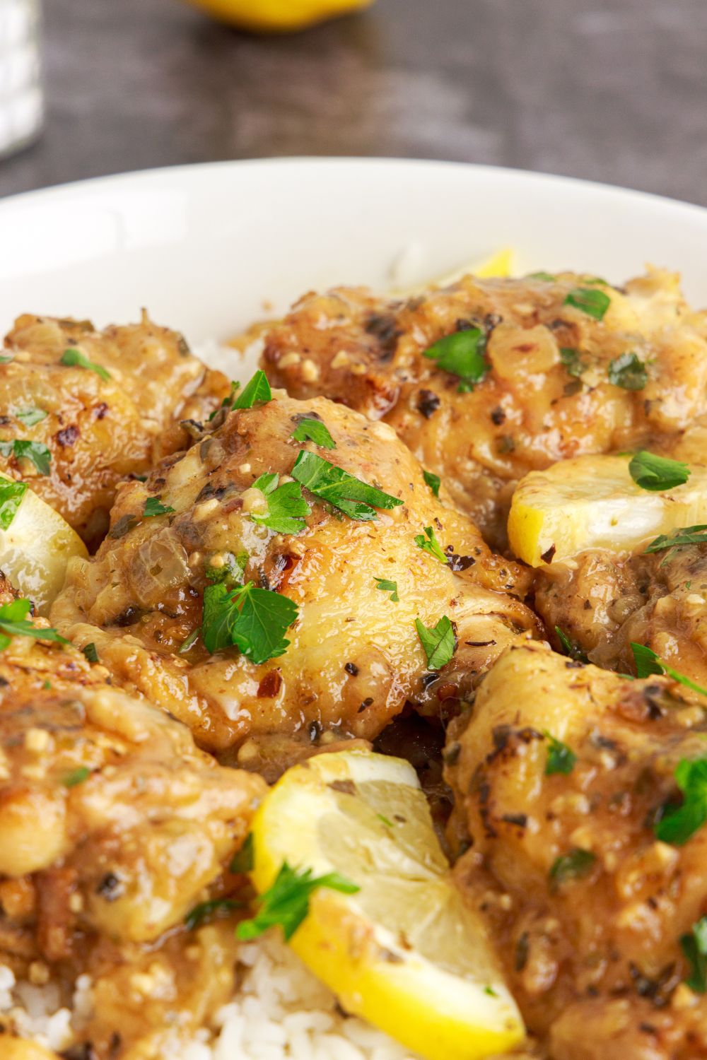 Instant Pot Lemon Butter Chicken placed on plate with some fresh parsley on top and lemon wedges 