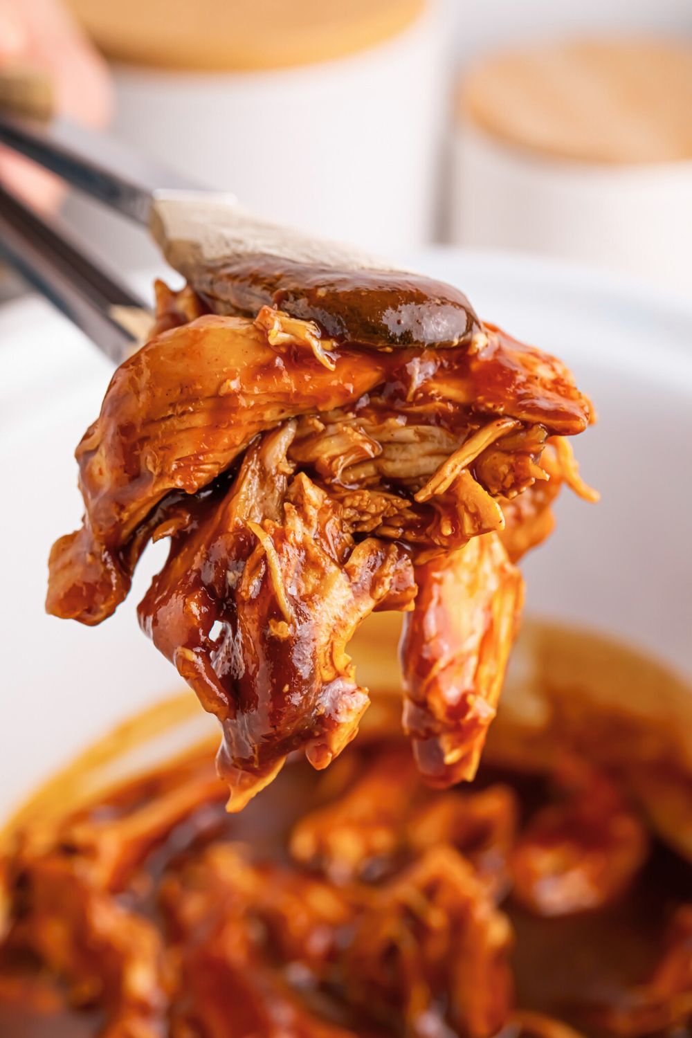 Crockpot Apple Butter BBQ Pulled Chicken being lifted out of crockpot with tongs 