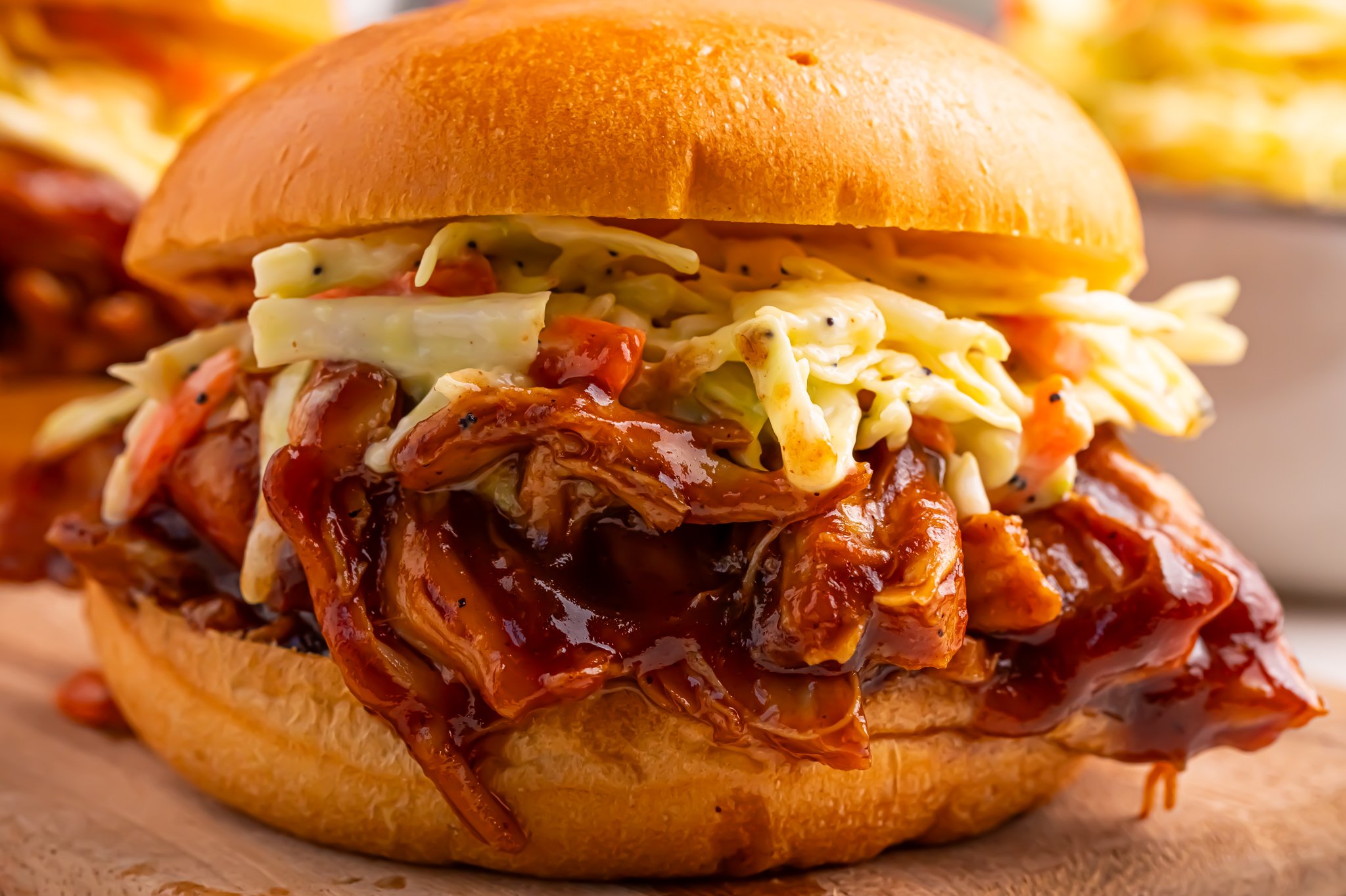 Crockpot Apple Butter BBQ Pulled Chicken sandwich on table with some coleslaw on top of meat 