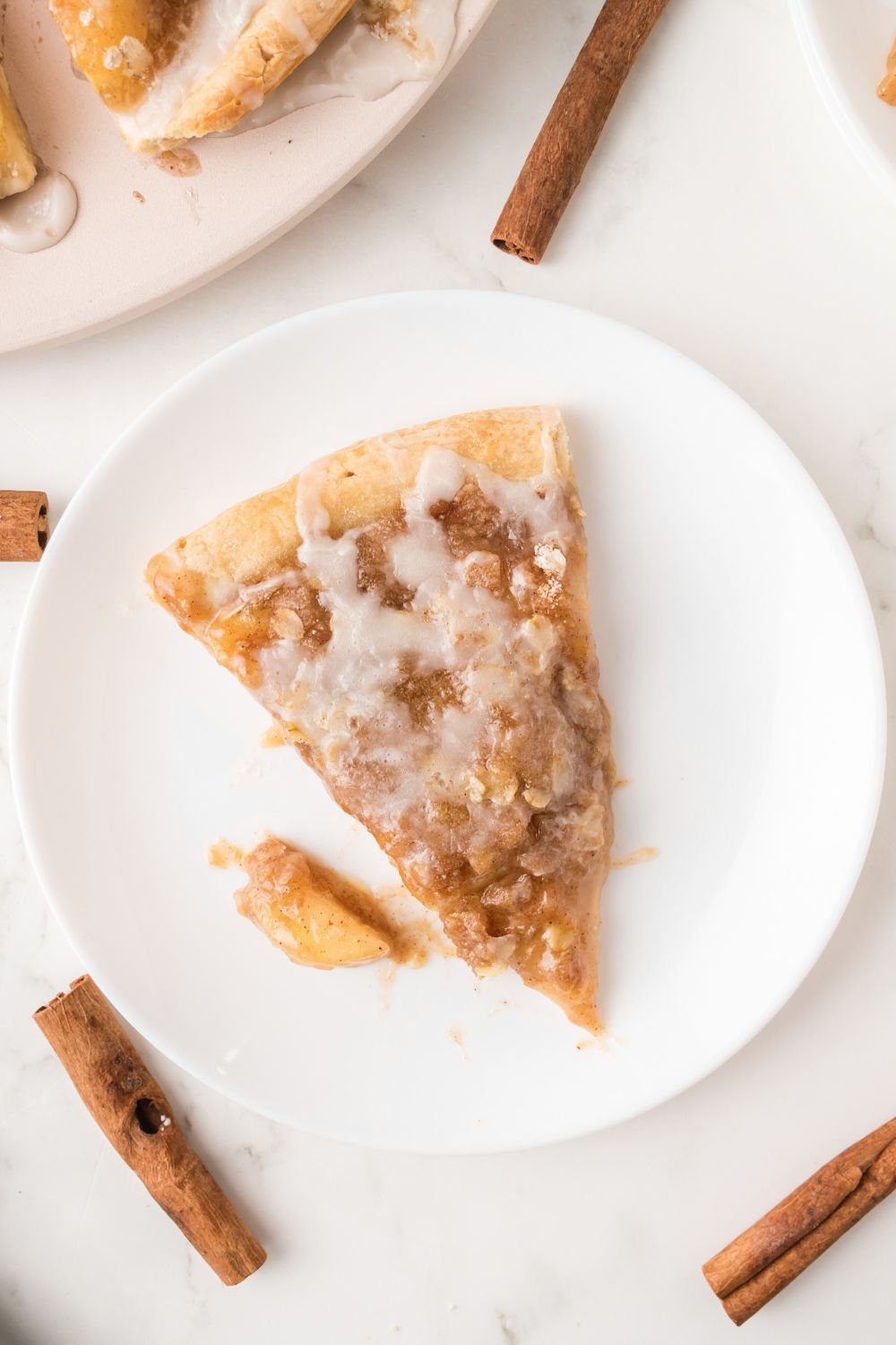 Apple Pie Pizza sliced and placed on plate with a few cinnamon sticks around table 