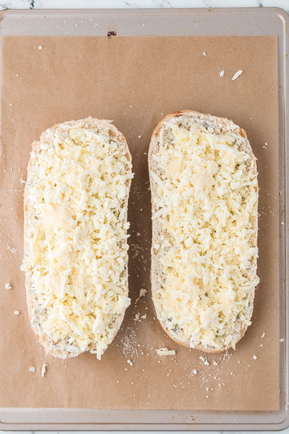 Cheesy Garlic Bread with cheese sprinkled over the top sitting on tray