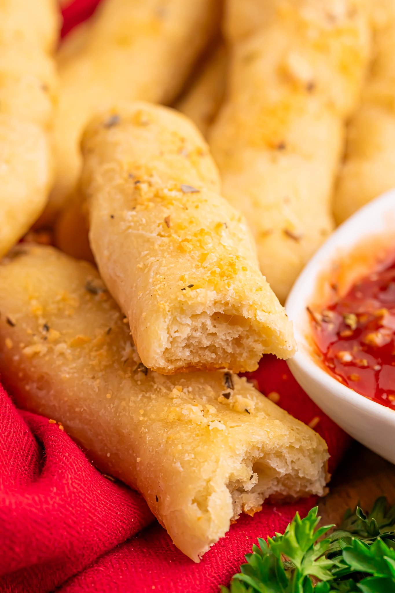 2 Ingredient Garlic Parmesan Breadsticks on table with one torn in half and a small bowl of marinara sauce