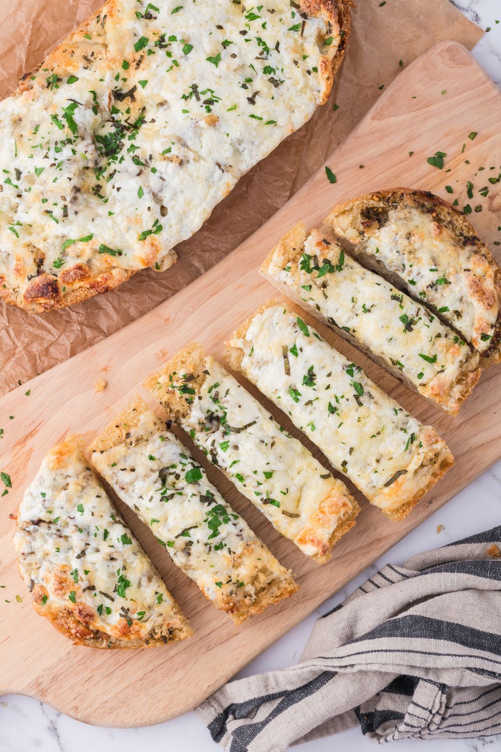 Cheesy Garlic Bread sliced on cutting board with another piece not cut