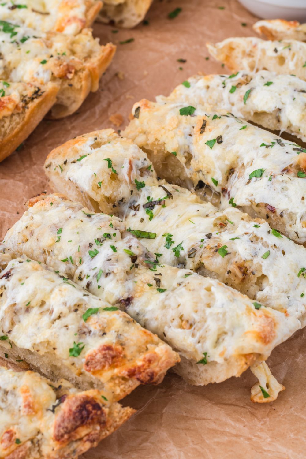 Cheesy Garlic Bread sliced into strips on cutting board 