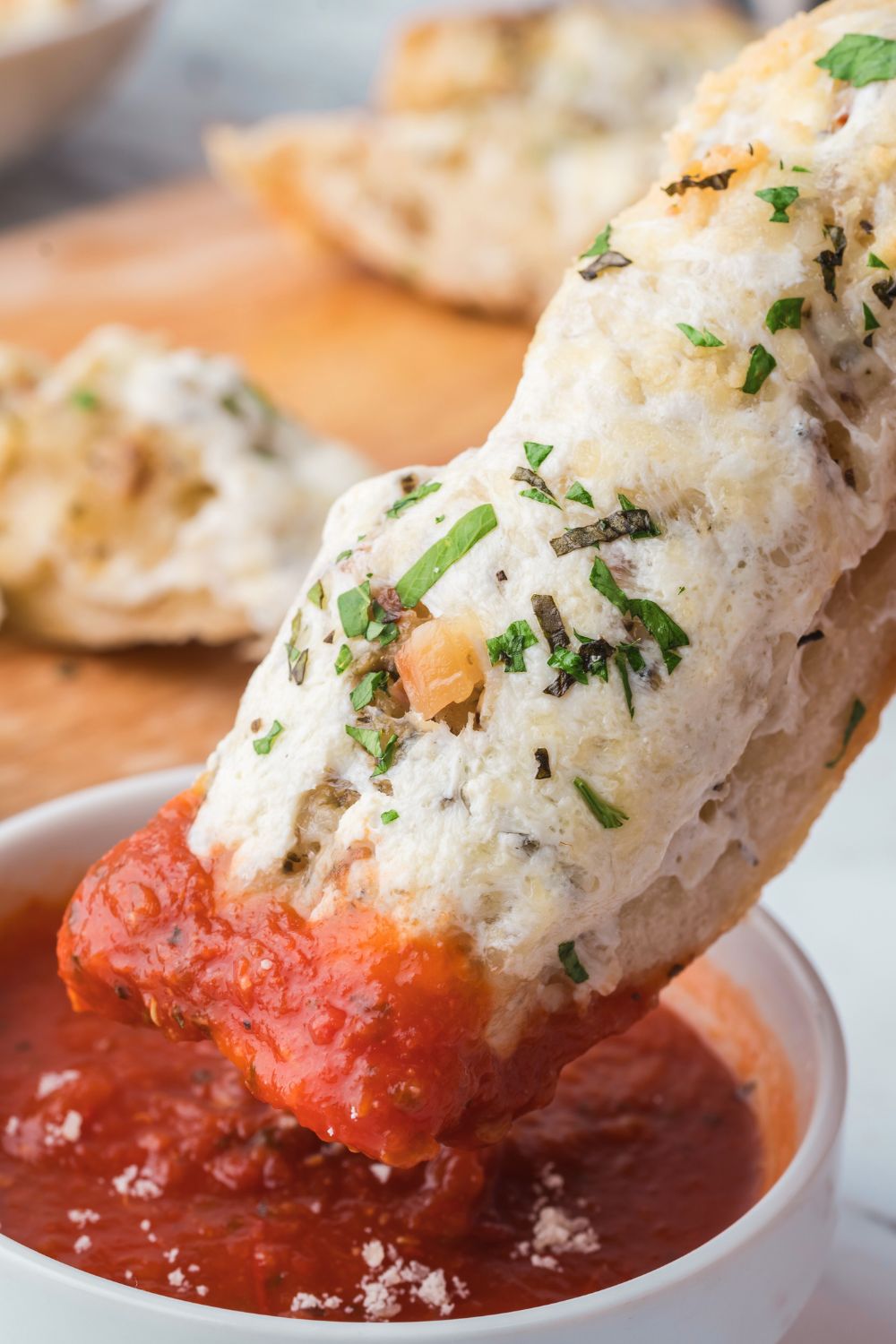 slice of Cheesy Garlic Bread dipping into marinara sauce 