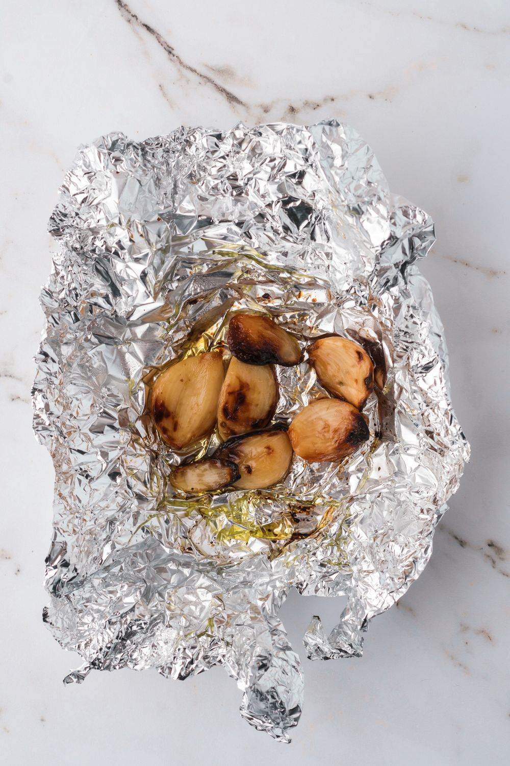 roasted garlic in foil sitting on table 