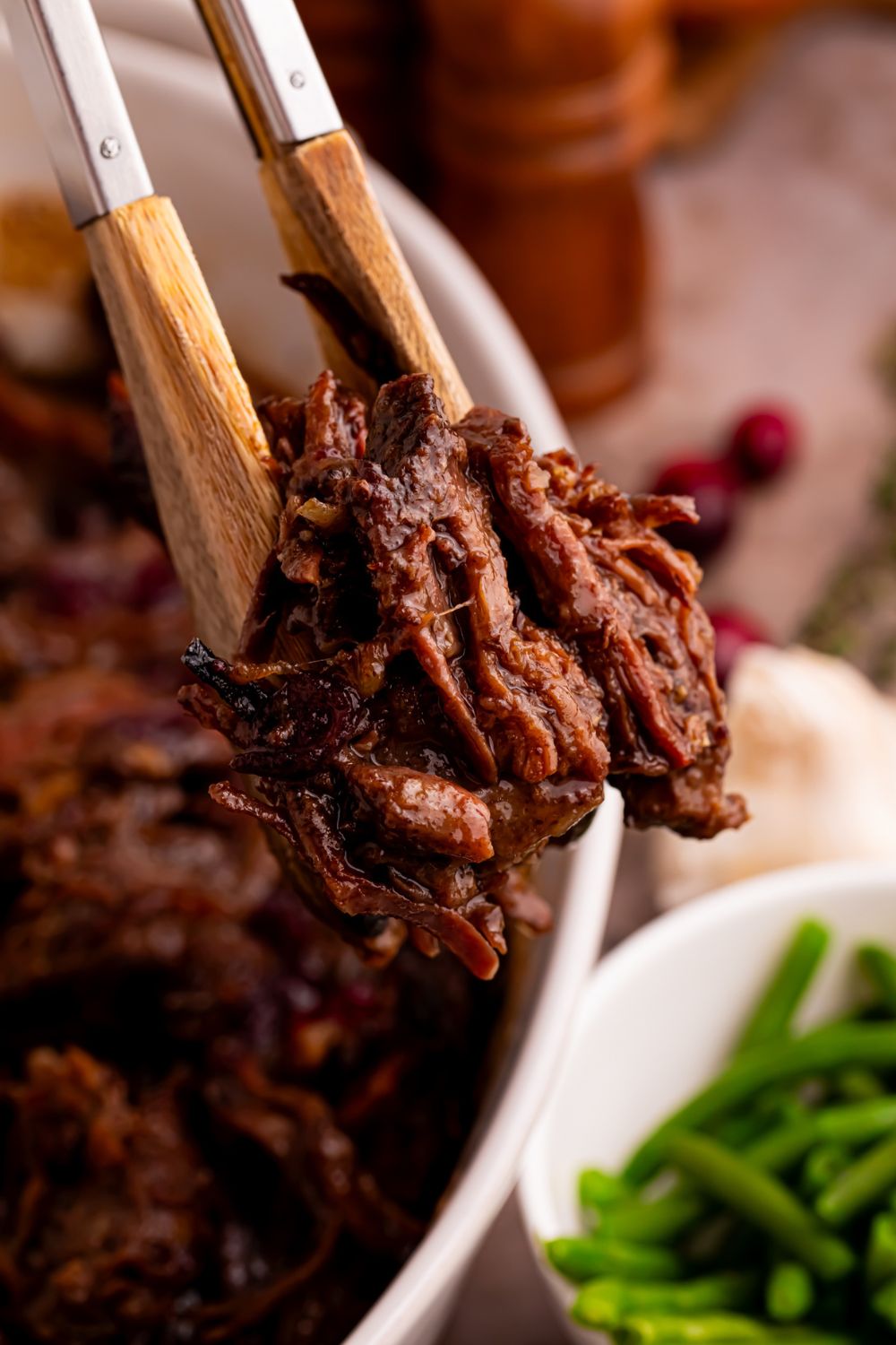 tongs with some shredded cranberry roast in it