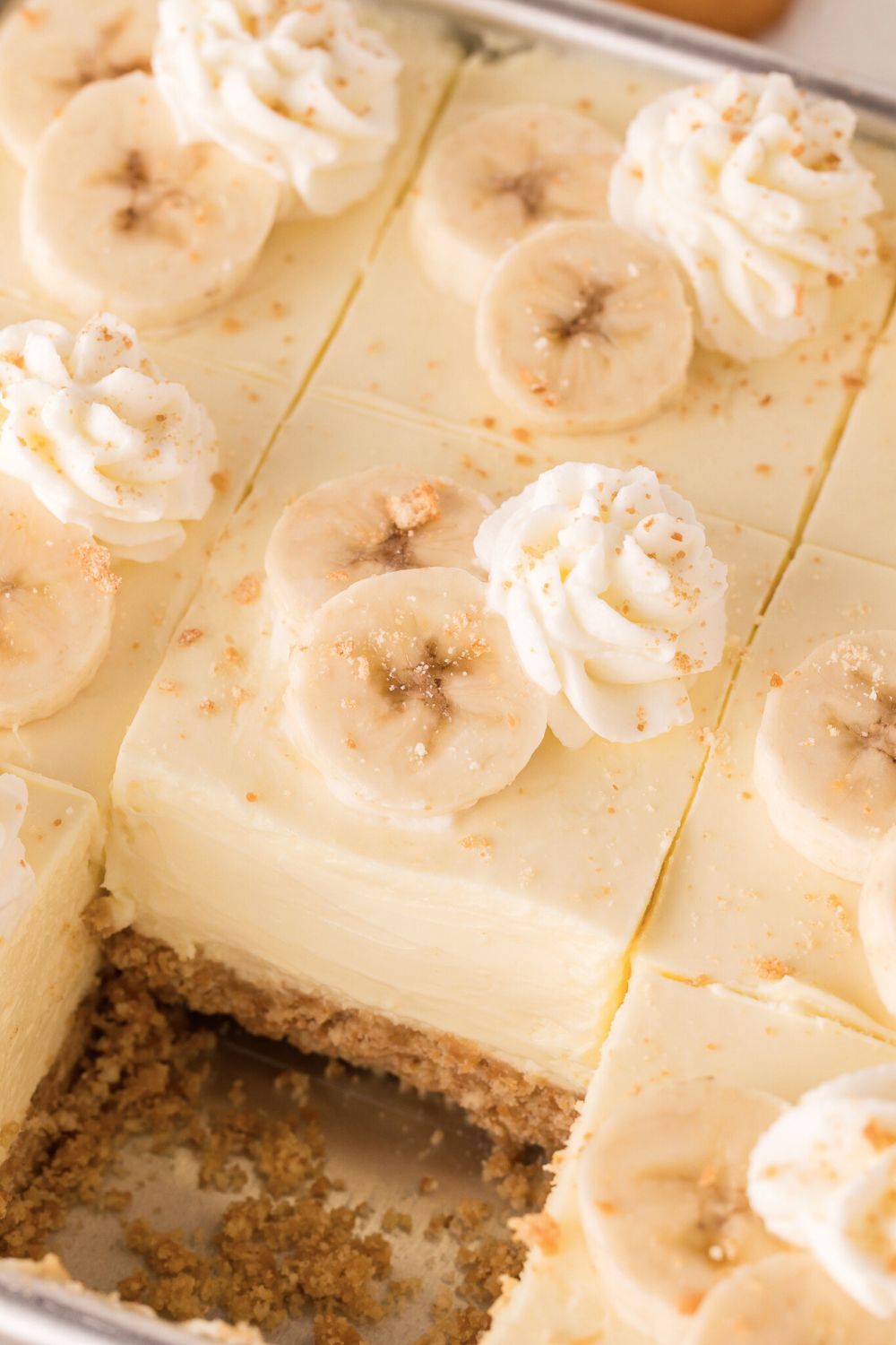 pan on table for No Bake Banana Pudding Cheesecake Bars with one slice taken out of it 